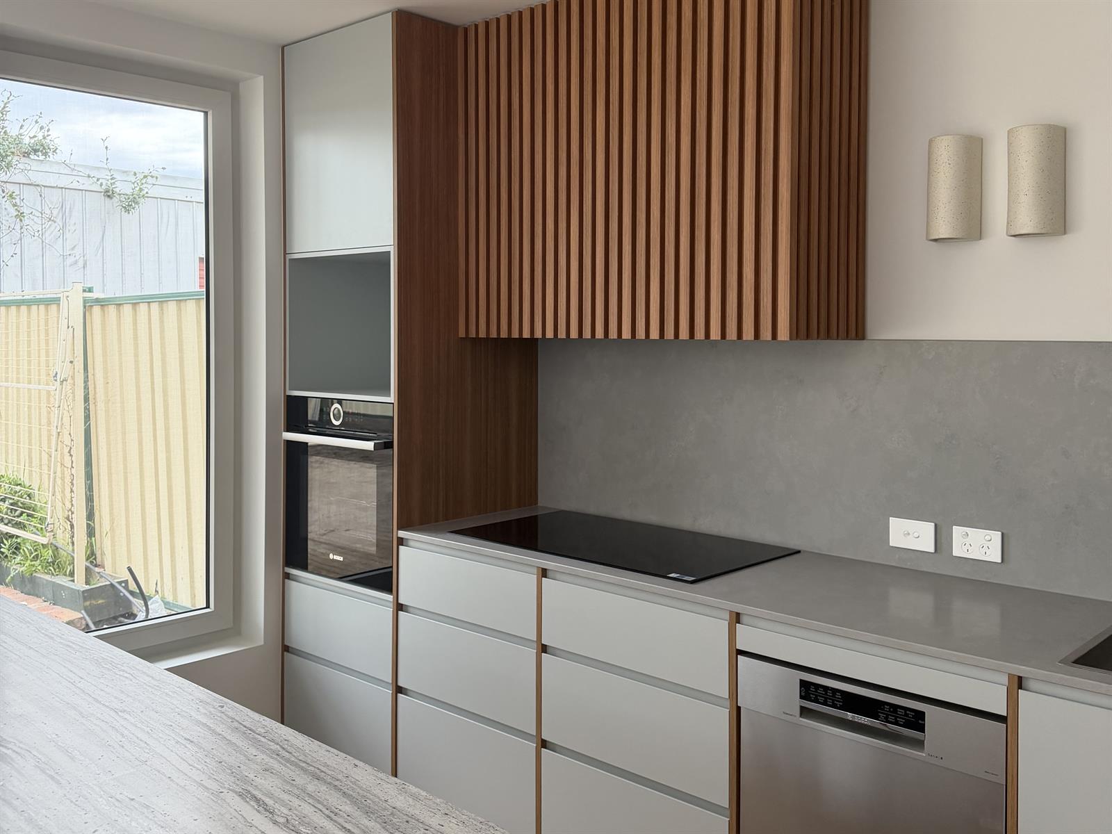 Contemporary kitchen with timber slat cabinetry, stone island, and white joinery
